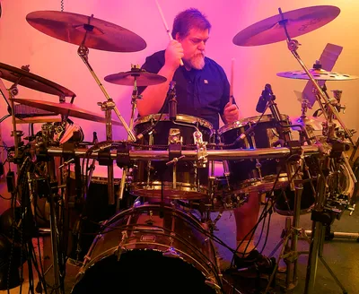 Jim Dooley behind his kit under magenta stage lighting
